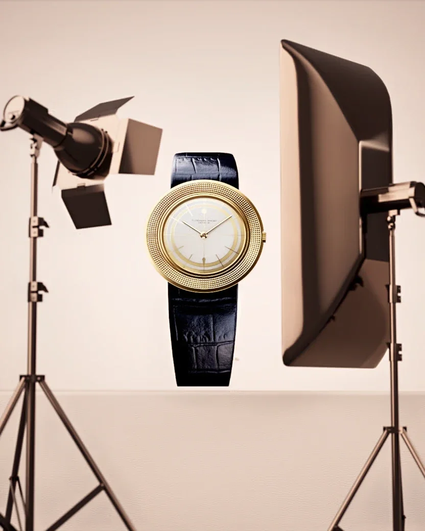 Fotostudio mit Scheinwerfern und Softbox, in der Mitte eine Uhr mit Goldgehäuse, hellem Zifferblatt und dunklem Lederband